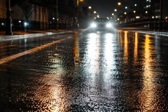 Dlaczego mokra jezdnia nocą oślepia mocniej? Sprawdź, jak warstwa wody zmienia odbicie światła, widoczność pasów i kontrast oraz dlaczego reflektory auta tworzą na asfalcie silne refleksy po deszczu.
